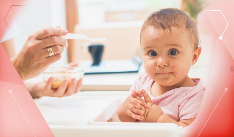 Ein Baby mit Rötungen und Ausschlag wegen einer falsch therapierten Kuhmilchallergie wird von seiner Mutter gefüttert.